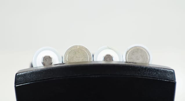 Fast charging of AA batteries. Rechargeable batteries in a black charger with four battery cells on a white background