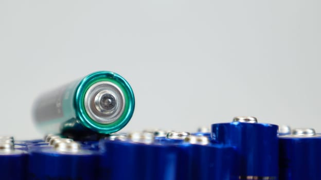 Lots of AA and AAA alkaline batteries on a white background. Ecological recycling concept. The terminals of the disposable batteries are close together and form a beautiful backdrop. Energy source