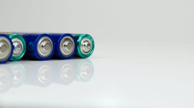 AA alkaline rechargeable batteries on white glossy background with reflection with copy space
