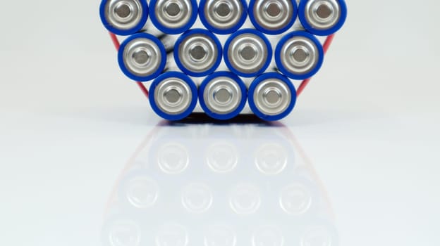 Lots of AA and AAA alkaline batteries on a white background. Ecological recycling concept. The terminals of the disposable batteries are close together and form a beautiful backdrop. Energy source