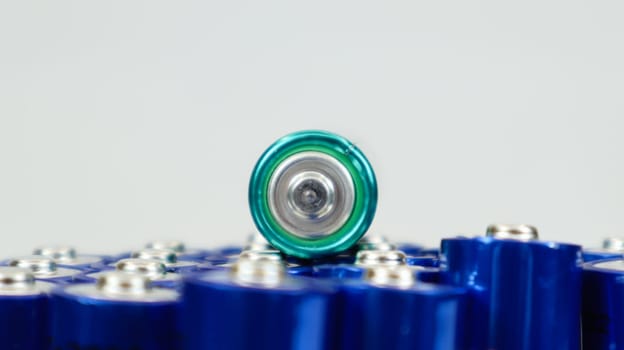 Lots of AA and AAA alkaline batteries on a white background. Ecological recycling concept. The terminals of the disposable batteries are close together and form a beautiful backdrop. Energy source