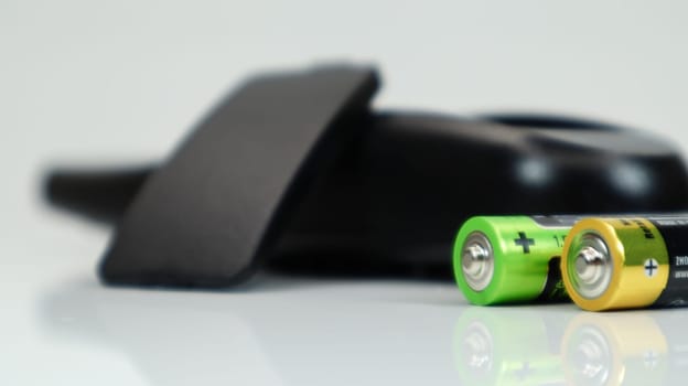 Black TV remote control with AAA alkaline batteries on a white background. Battery replacement, spare parts. Close up of the battery compartment of the remote control