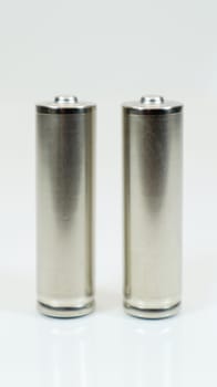 AA alkaline rechargeable batteries on white glossy background with reflection. Close up two empty batteries with copy space. Vertical photography
