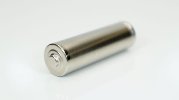 AA alkaline rechargeable battery on white glossy background with reflection. Close one empty battery with copy space