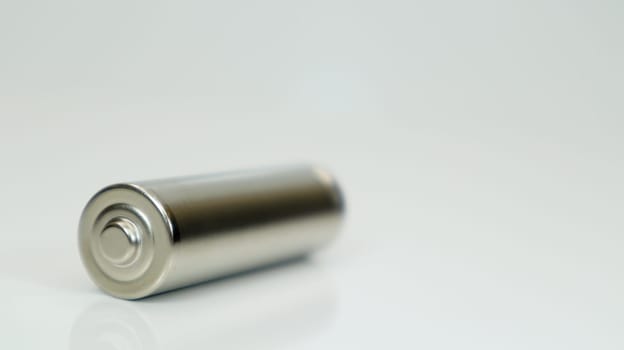 AA alkaline rechargeable battery on white glossy background with reflection. Close one empty battery with copy space
