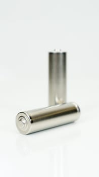 AA alkaline rechargeable batteries on white glossy background with reflection. Close up two empty batteries with copy space. Vertical photography