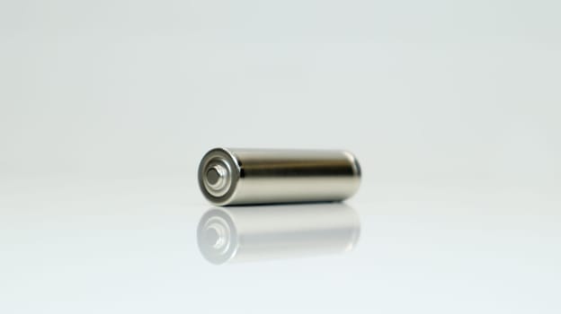 AA alkaline rechargeable battery on white glossy background with reflection. Close one empty battery with copy space
