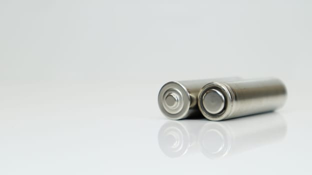 AA alkaline rechargeable batteries on white glossy background with reflection. Close up two empty batteries with copy space