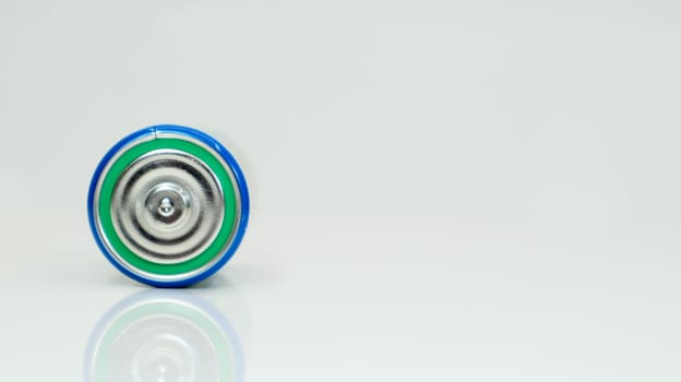 Large battery type D or C cell on white background with reflection. View of a metallic alkaline battery with copy space. Mandatory processing