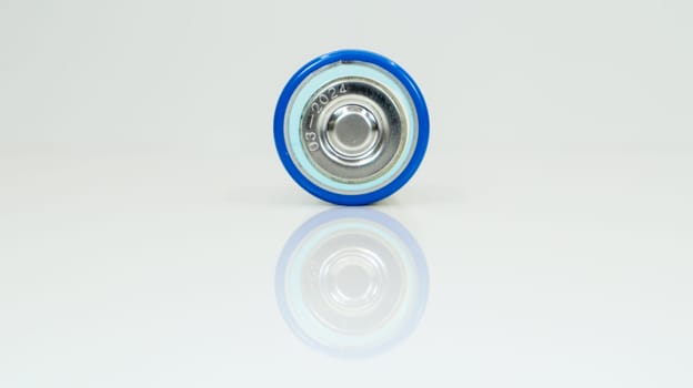 Large battery type D or C cell on white background with reflection. View of a metallic alkaline battery with copy space. Mandatory processing