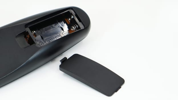 Black TV remote control with AAA alkaline batteries on a white background. Battery replacement, spare parts. Close up of an empty battery compartment of the remote control