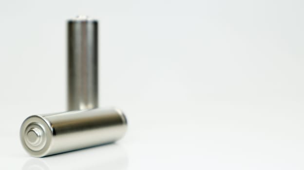 AA alkaline rechargeable batteries on white glossy background with reflection. Close up two empty batteries with copy space