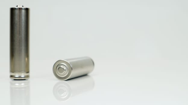 AA alkaline rechargeable batteries on white glossy background with reflection. Close up two empty batteries with copy space
