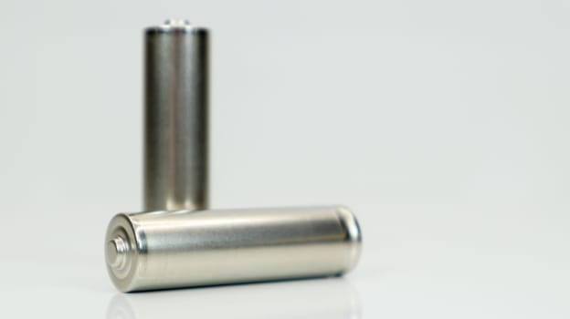 AA alkaline rechargeable batteries on white glossy background with reflection. Close up two empty batteries with copy space