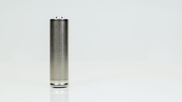 AA alkaline rechargeable battery on white glossy background with reflection. Close one empty battery with copy space