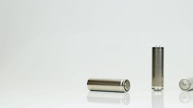 AA alkaline rechargeable batteries on white glossy background with reflection. Close up three empty batteries with copy space