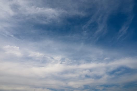 Fluffy white clouds drift gracefully in the expansive azure sky, creating a serene midday atmosphere.