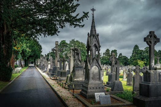 Dublin, Ireland, August 2019 Ancient graves with Celtic crosses and sculptures in Glasnevin Cemetery with dramatic storm sky in background