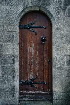 Vintage, old wooden door in Celtic or Gothic style with iron hinge and frame ornaments in mausoleum, Glasnevin Cemetery, Dublin, Ireland