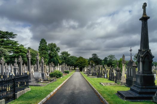 Dublin, Ireland, August 2019 Alley leading through Glasnevin Cemetery between graves with Celtic crosses and sculptures
