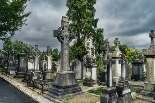 Dublin, Ireland, August 2019 Ancient graves with Celtic crosses and sculptures in Glasnevin Cemetery with dramatic storm sky in background