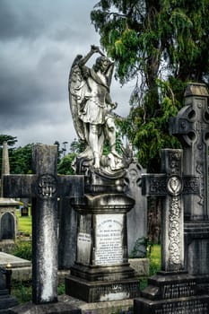 Dublin, Ireland, August 2019 Archangel Michael as a warrior saint slaying a dragon, graves with Celtic crosses and sculptures in Glasnevin Cemetery