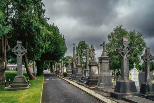 Dublin, Ireland, August 2019 Ancient graves with Celtic crosses and sculptures in Glasnevin Cemetery with dramatic storm sky in background