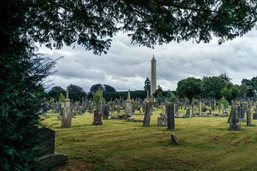Dublin, Ireland, August 2019 Ancient graves and tombstones in Glasnevin Cemetery with Round Tower in background