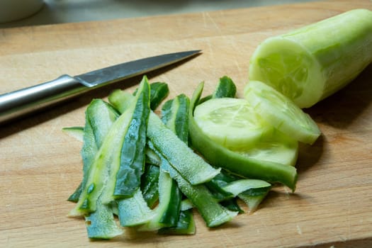 Peelings and sliced cucumber on a wooden board
