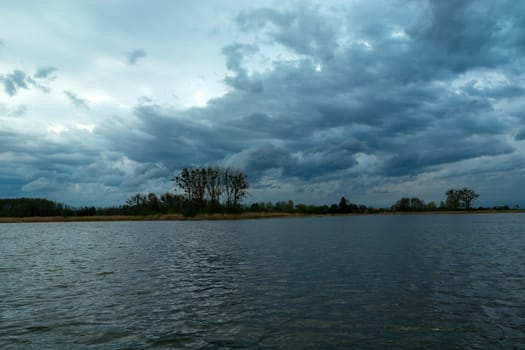 Restless evening clouds over a calm lake, spring view in Stankow, Poland