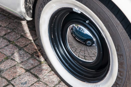 Esens, Germany - September 19, 2021: Reflection of a German classic car in the hubcap of another classic car at the classic car meeting in Esens.