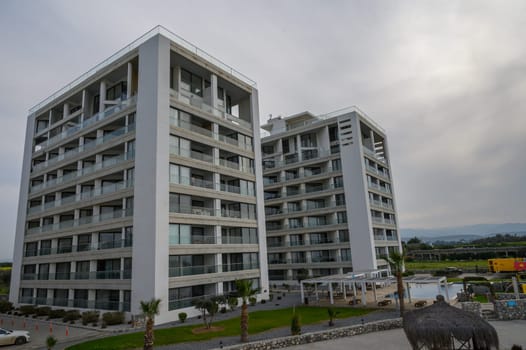 Two modern buildings tower over a serene area with palm trees and outdoor amenities nearby.