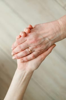 Hand of young girl holds hand of elderly mother. Older generation support.