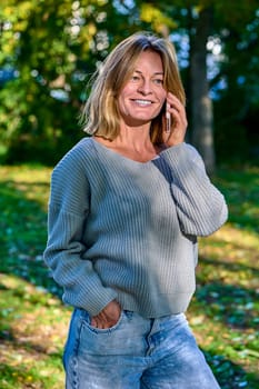 Beautiful woman talking on the phone in the park in summer. High quality photo