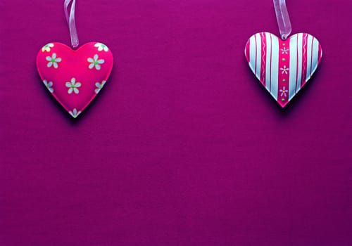Two white pink metal hearts on a dark pink paper background