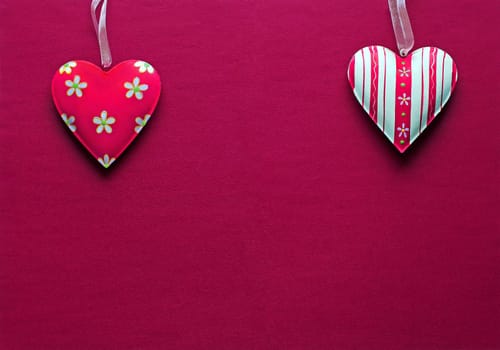 Two white pink metal hearts on a dark pink paper background
