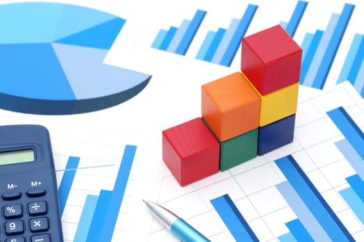 colorful wooden blocks with graph printed documents on white background
