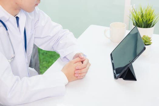 Happy Asian young doctor handsome man smile wear glasses use modern smart digital tablet computer sit and listen patient explain symptoms on desk at hospital office, Technology Healthcare And Medicine
