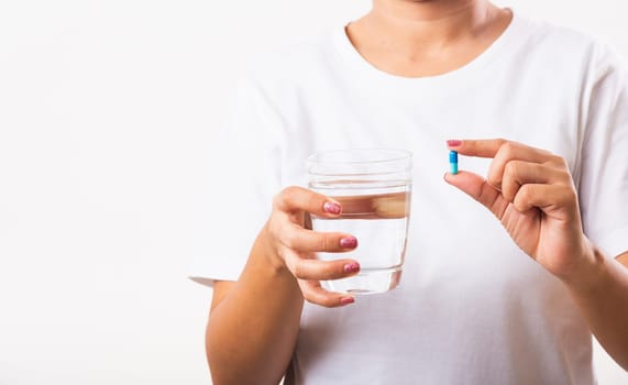 Closeup young Asian woman hold pill drugs in hand ready take medicines with a glass of water, studio shot isolated on white background, Healthcare and medical pharmacy concept