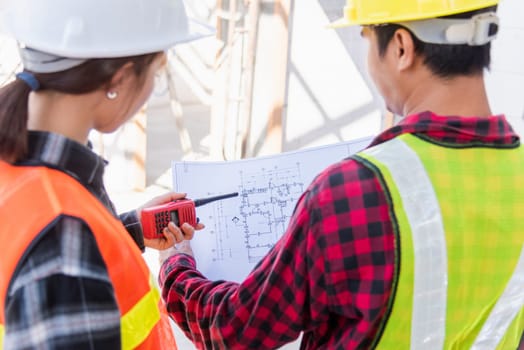 Architect and client discussing the plan with blueprint of the building at construction site. Asian engineer foreman worker man and woman working talking on drawing paper to checking project