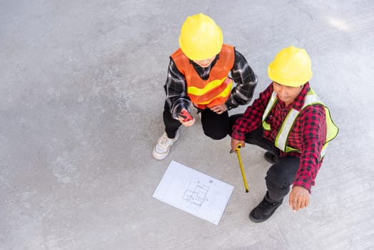 Architect and client discuss help create plan with blueprint of the building at construction site floor. Asian engineer foreman worker man and woman meeting talking on drawing paper project, top view