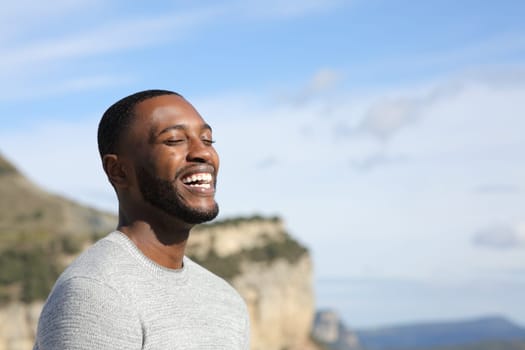Funny man with black skin laughing outdoors with copy space