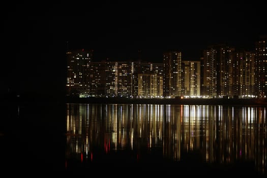 night cityscape light in the windows of skyscrapers is reflected in the river