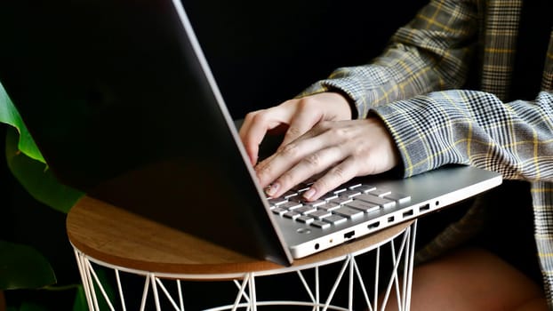 Close-up of woman's hands in a jacket typing on a laptop computer. The person works, studies at home online. No face.