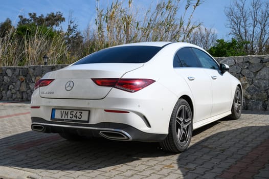 Gaziveren Cyprus -15.02.2025 A sleek sedan basks in the sun, framed by greenery and textured stone, creating a serene vibe.