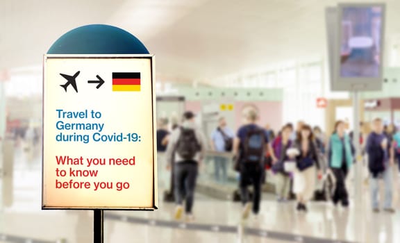 a signal inside an airport that warns about what to know before flying to Germany during the Covid-19 pandemic. Airport security measures and travel restrictions. New Covid-19 variant spread