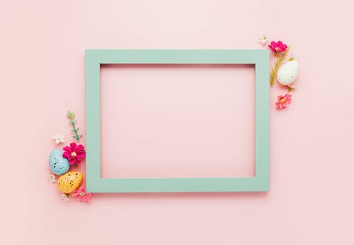 Easter holiday pink mockup background. Top view from above to different colorful Easter eggs, flowers, picture frame border. Card with copy space to place text. Minimal flat lay. High quality photo