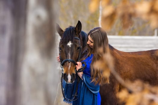 Touching portrait of a girl in a blue dress with a horse