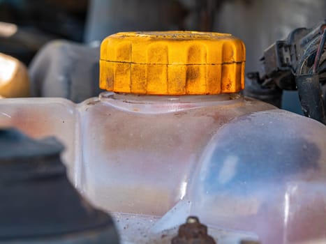 Plastic tank with a yellow cap for antifreeze of the car engine cooling system. Plastic tank with yellow lid. Liquid container. Refueling antifreeze. Car repair. Customer Service. Coolant.