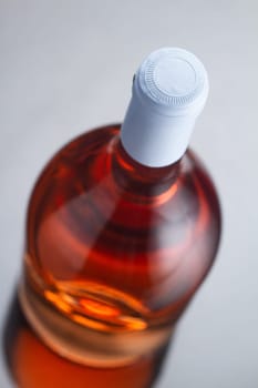 top view closeup of rose wine bottle mockup with light blue blank cap enclosure in focus